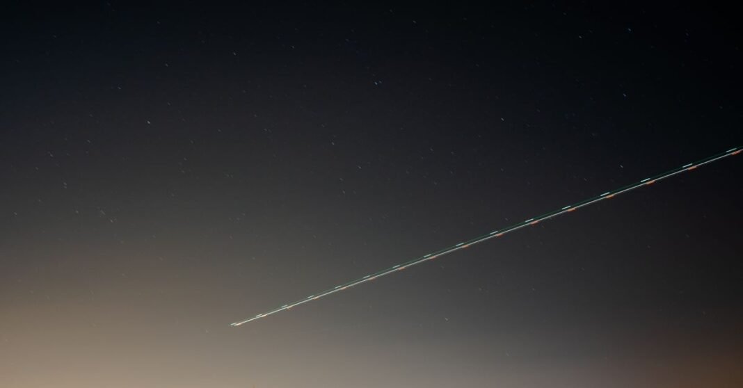 Un cielo nocturno sereno sobre el campo con una estela de luz y estrellas distantes en Madrid, España.
