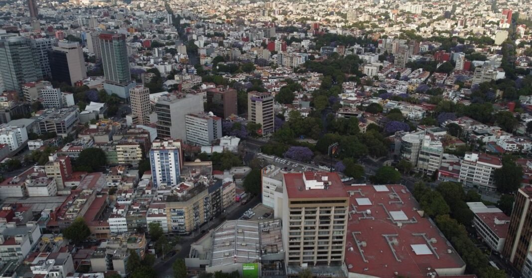 PIB de México rebota 1.5% en el segundo trimestre, impulsado por factores temporales Amplia vista aérea de Ciudad de México que muestra un denso diseño urbano con el estadio deportivo visible.
