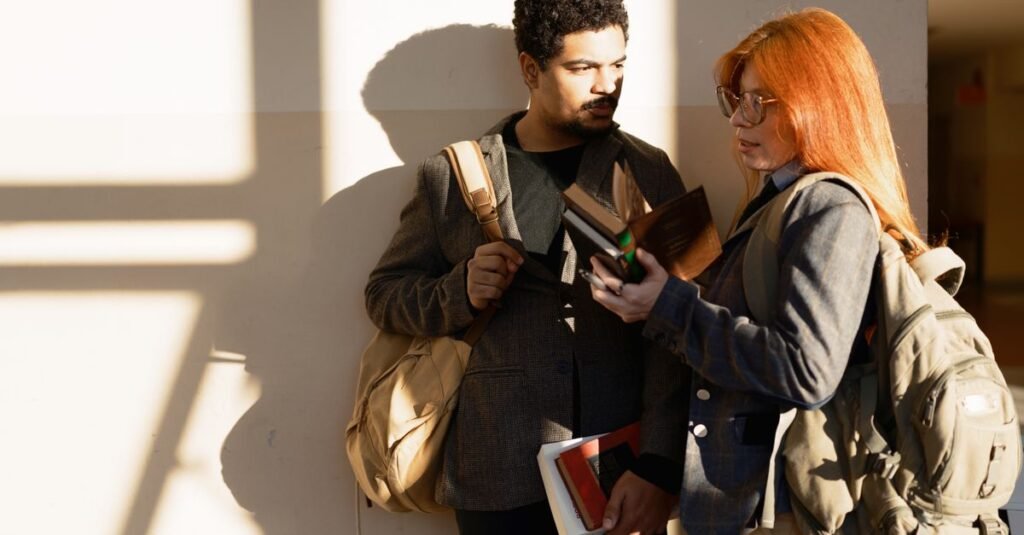 Dos estudiantes conversando sobre un libro en un pasillo soleado del campus de Buenos Aires.