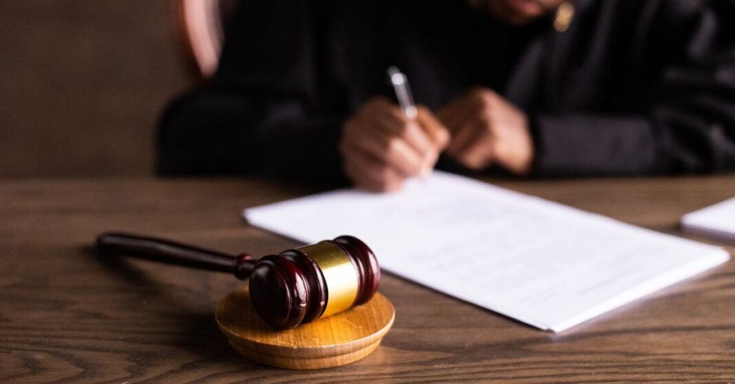 Orden de captura contra Evo Morales por terrorismo y sedición corresponde a un proceso de 2019 Juez firmando documentos en el escritorio con enfoque en el mazo, representando la ley y la justicia.
