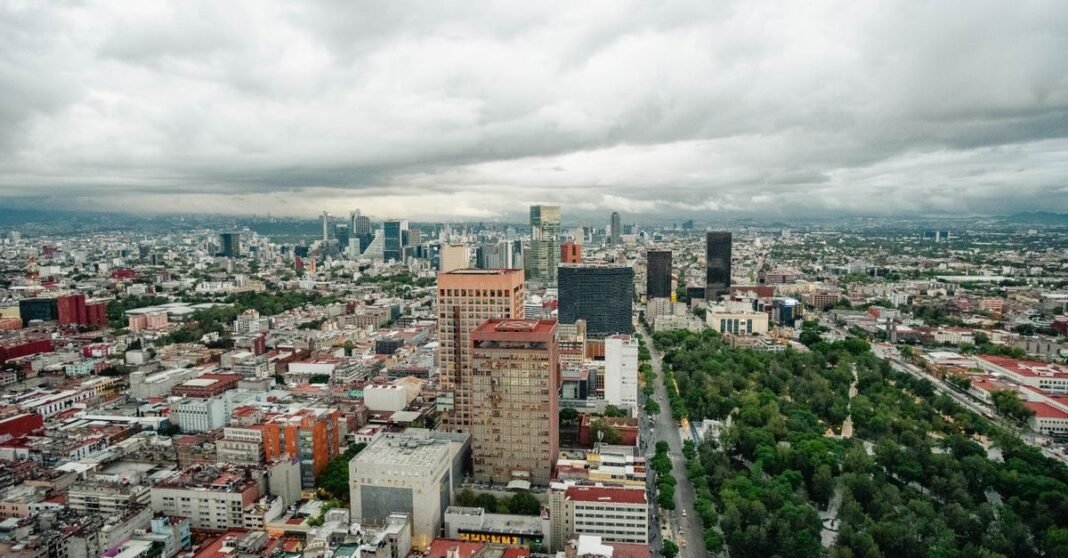 Inundaciones en la CDMX evidencian rezagos en el drenaje y costos crecientes para la ciudad Coches y peatones en una calle urbana concurrida en Ciudad de México, bordeada de árboles y edificios.
