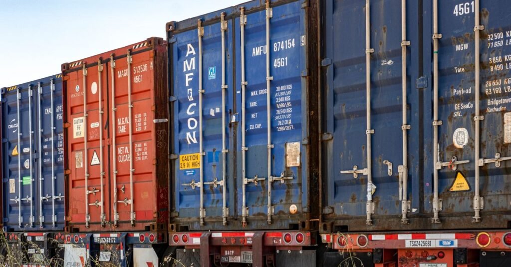 Fila de contenedores de carga coloridos en un patio de envío industrial, listos para el transporte.