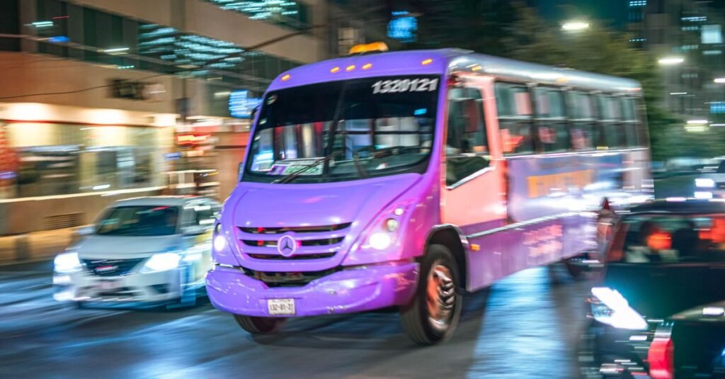 Escena de una parada de autobús con edificios coloridos en Ciudad de México, mostrando la vida urbana local.
