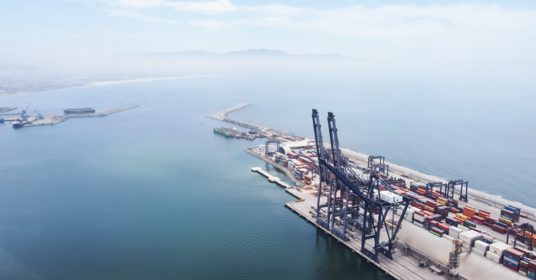 Exportaciones mexicanas a Estados Unidos crecen 13% en el primer semestre de 2026 Una toma aérea panorámica que captura la logística y los buques de contenedores en el Puerto de Ensenada, Baja California.