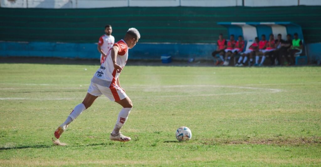 Atletas jugando al fútbol en un partido competitivo en un campo verde vibrante.