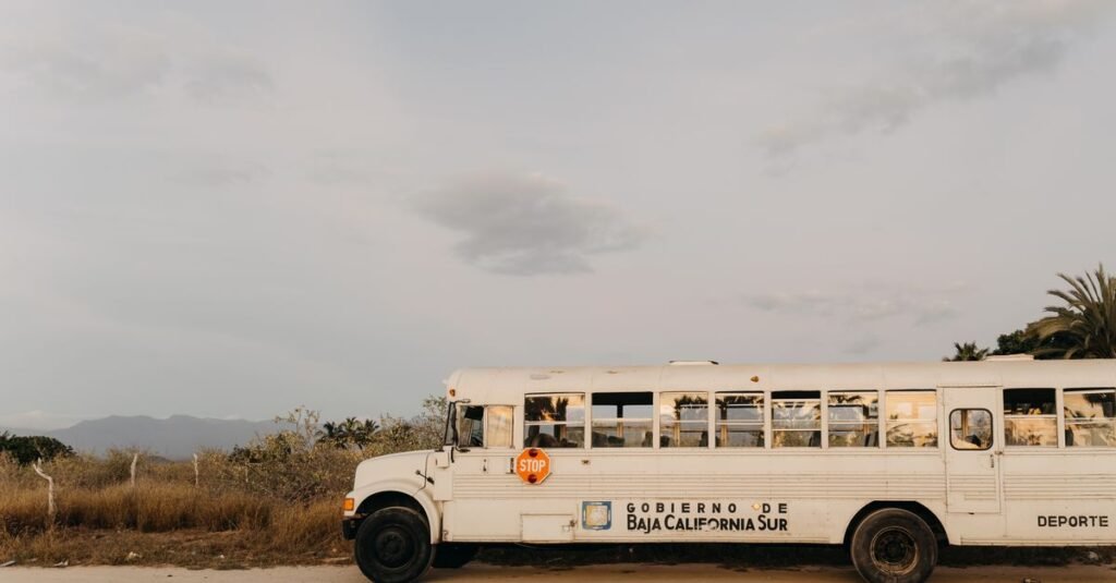 Un autobús escolar blanco estacionado en el paisaje desértico de Baja California Sur, México, bajo un cielo claro.