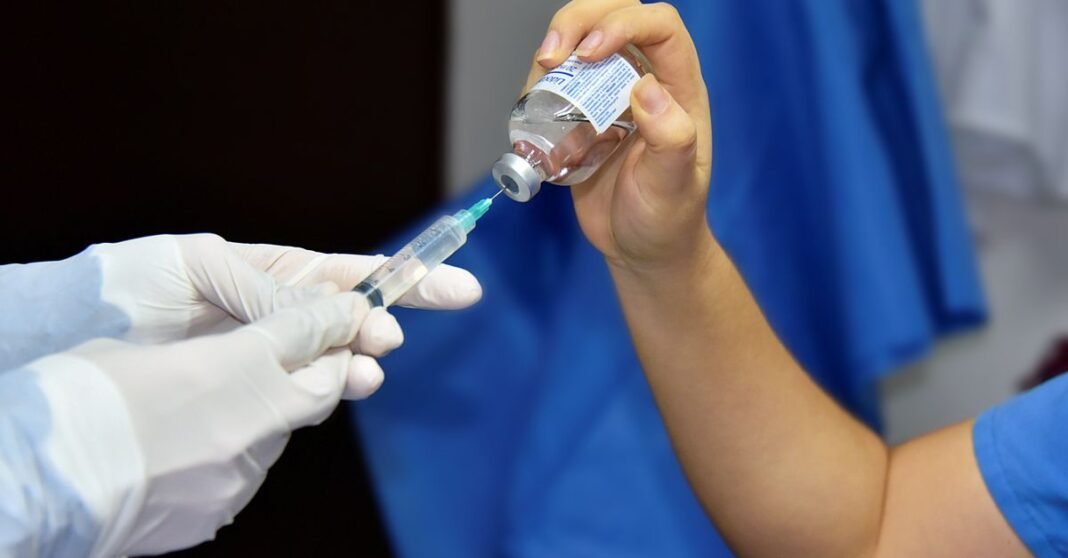 Imagen ilustrativa: La naloxona sigue en discusión legislativa: Senado impulsa facilitar su acceso ante sobredosis por opioides Primer plano de un trabajador de la salud llenando una jeringa desde un vial, demostrando vacunación o procedimiento médico.