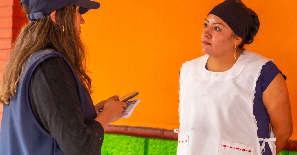 Dos mujeres conversando cerca de una pared colorida en Ciudad de México, destacando la vida urbana y la interacción.