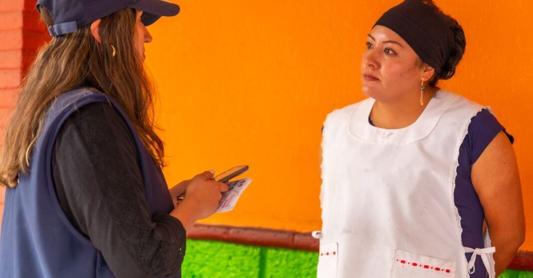 CDMX presenta Pacto Digital y anuncia decálogo sobre uso de celulares para infancias y adolescencias Dos mujeres conversando cerca de una pared colorida en Ciudad de México, destacando la vida urbana y la interacción.