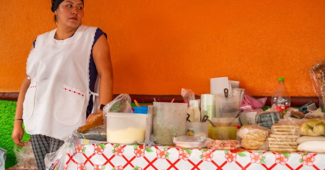 CDMX prevé invertir 100 mdp en capital semilla para impulsar 4 mil negocios de mujeres Dos mujeres conversando cerca de una pared colorida en Ciudad de México, destacando la vida urbana y la interacción.