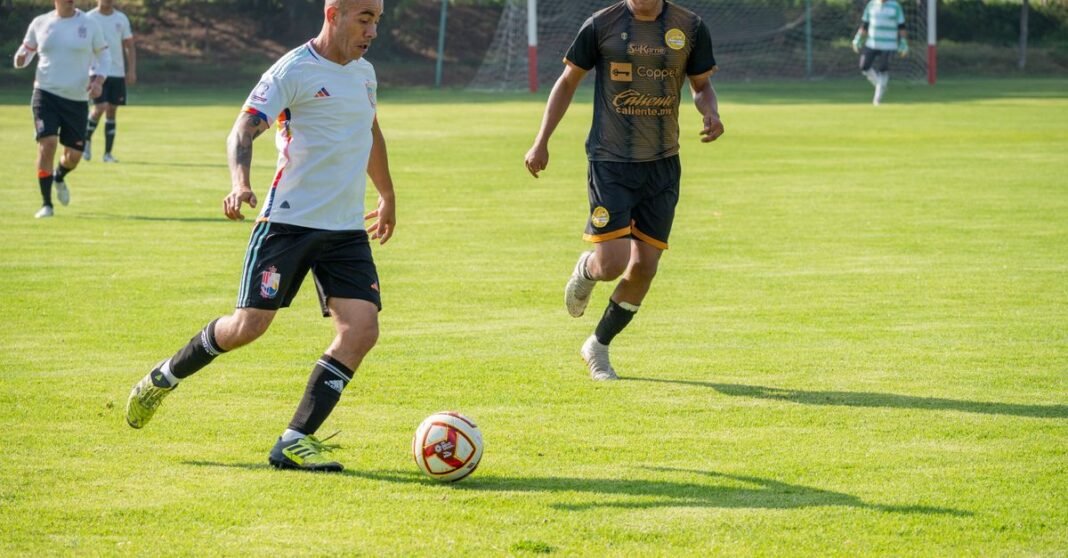 Reportes desde Brasil colocan a Luiz Felipe Scolari como posible técnico de la Selección mexicana Atletas jugando al fútbol en un partido competitivo en un campo verde vibrante.