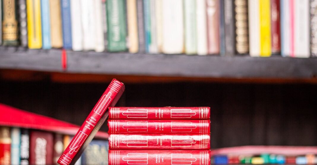 Muere José Agustín, referente de la narrativa mexicana y la contracultura Pila de libros rojos con fondo de estantería, ideal para temas de biblioteca.