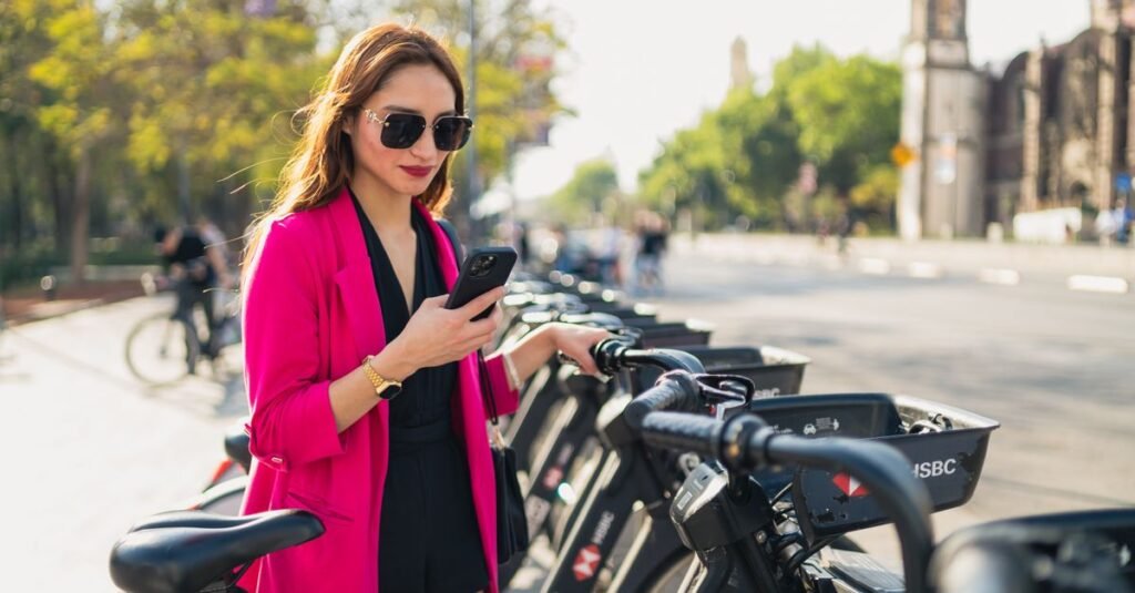 Una mujer a la moda revisa su teléfono junto a una estación de bicicletas en la Ciudad de México.
