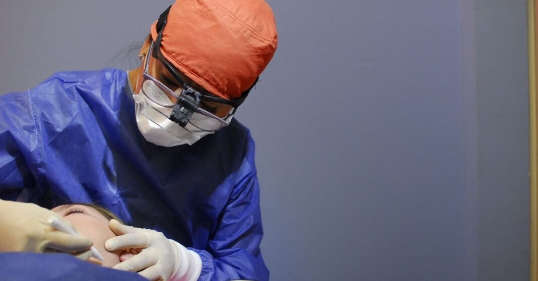 IMSS capacita a residentes de urgencias para mejorar la atención del evento vascular cerebral Equipo de cirujanos realizando un procedimiento quirúrgico bajo luces brillantes en un quirófano moderno en México.