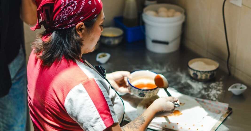 Una mujer prepara comida mexicana en la cocina, destacando prácticas culinarias tradicionales.