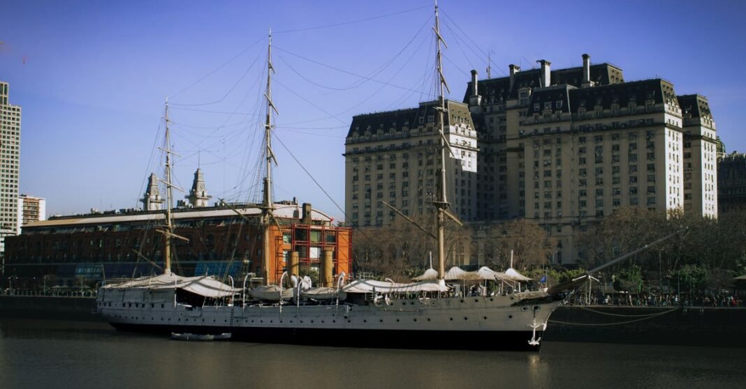 Buenos Aires recibe la conferencia internacional de la DEA sobre combate al narcotráfico Un barco a vela clásico atracado en Puerto Madero con un fondo de paisaje urbano, bajo un cielo azul claro.