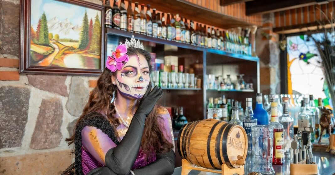 Fátima Bosch gana Miss Universo 2025 tras la polémica por su humillación en el certamen Una mujer con maquillaje de La Catrina posa en un bar mexicano animado, celebrando el Día de los Muertos.