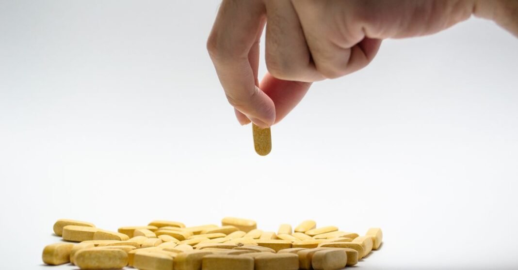 Desabasto de medicamentos en México: 7.5 millones de recetas no surtidas en 2023, según Cero Desabasto Primer plano de una mano que toma una pastilla amarilla de una pila de tabletas sobre una superficie blanca.