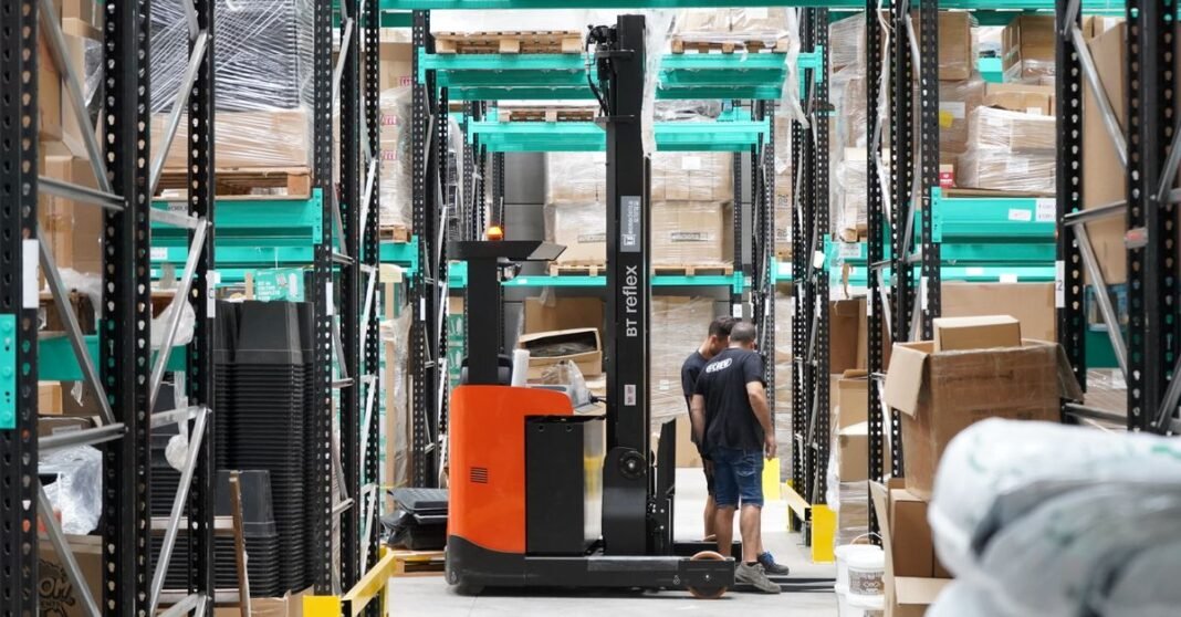 EE. UU. mantiene medidas distintas para lechuga, aguacate y ganado de México; restricción a jalapeño no fue confirmada Escena de almacén con trabajadores y una carretilla elevadora recorriendo pasillos para la gestión logística y de inventario.