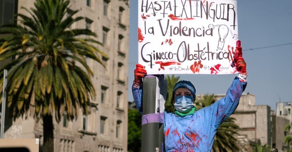 Una mujer participa en una protesta contra la violencia obstétrica en Ciudad de México, sosteniendo un cartel contundente.