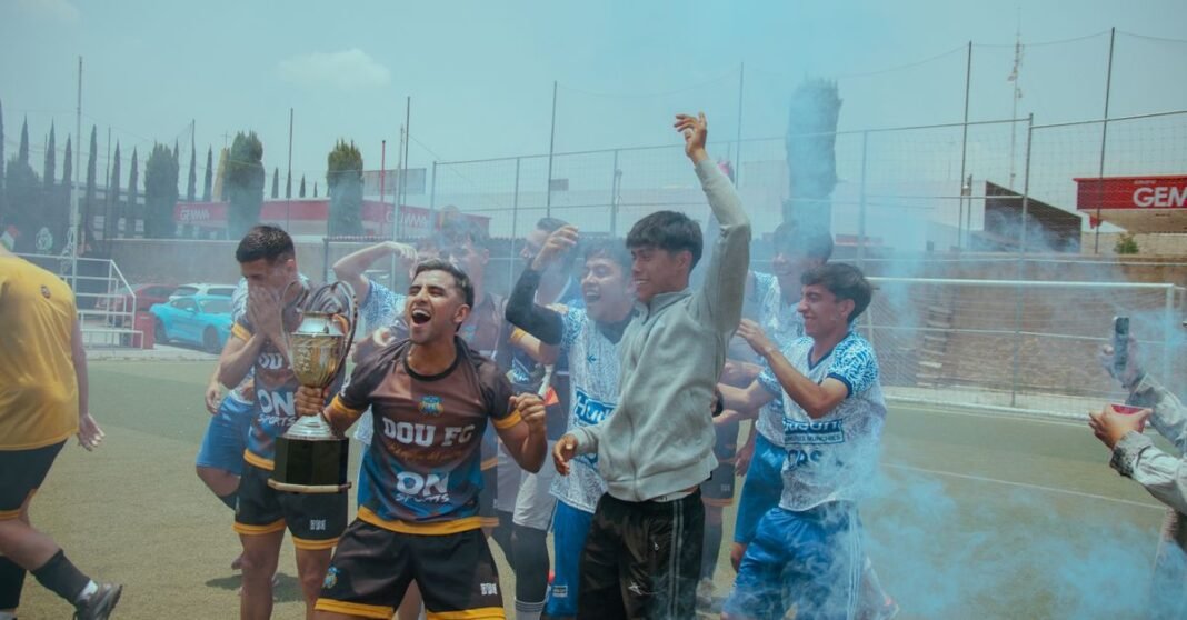 México Sub-15 conquista el Campeonato de Concacaf con goleada sobre Estados Unidos El equipo juvenil de fútbol celebra alegremente su victoria en el campeonato con un trofeo y humo de colores.