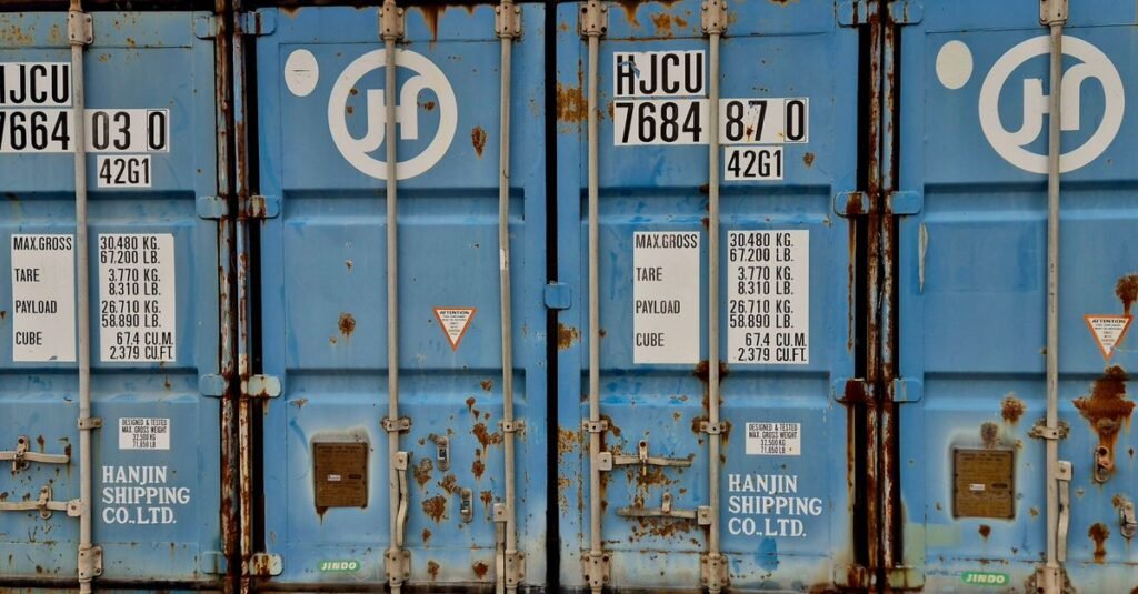 Primer plano de un contenedor de envío Hanjin azul oxidado que muestra información sobre peso y tamaño.