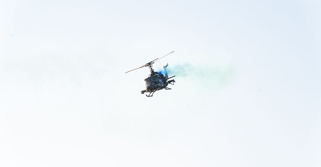 Mueren dos tripulantes tras choque de helicópteros que combatían incendio cerca de Atenas Helicóptero de gran altitud emitiendo humo azul en el cielo despejado de El Salvador.
