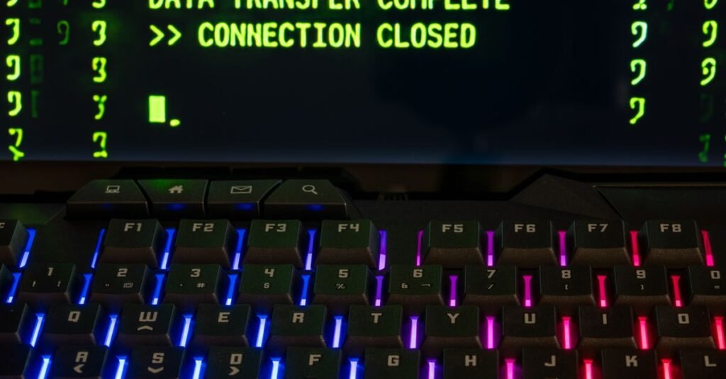 Primer plano de un teclado iluminado por RGB con una pantalla que muestra 'Transferencia de Datos Completa'.
