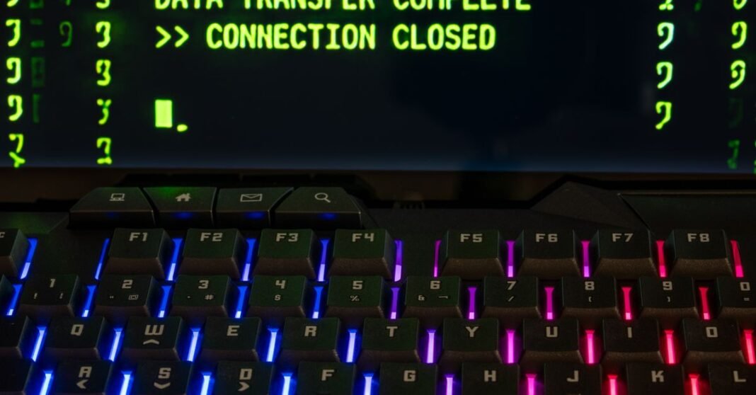 Deloitte detecta una brecha entre la confianza empresarial y la ejecución en ciberseguridad Primer plano de un teclado iluminado por RGB con una pantalla que muestra 'Transferencia de Datos Completa'.