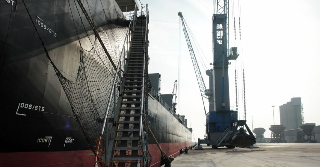 México aprueba aranceles de hasta 50% a importaciones de China y otros países sin tratado comercial Un buque de carga atracado en un puerto industrial, con una grúa y una red de seguridad a la vista.