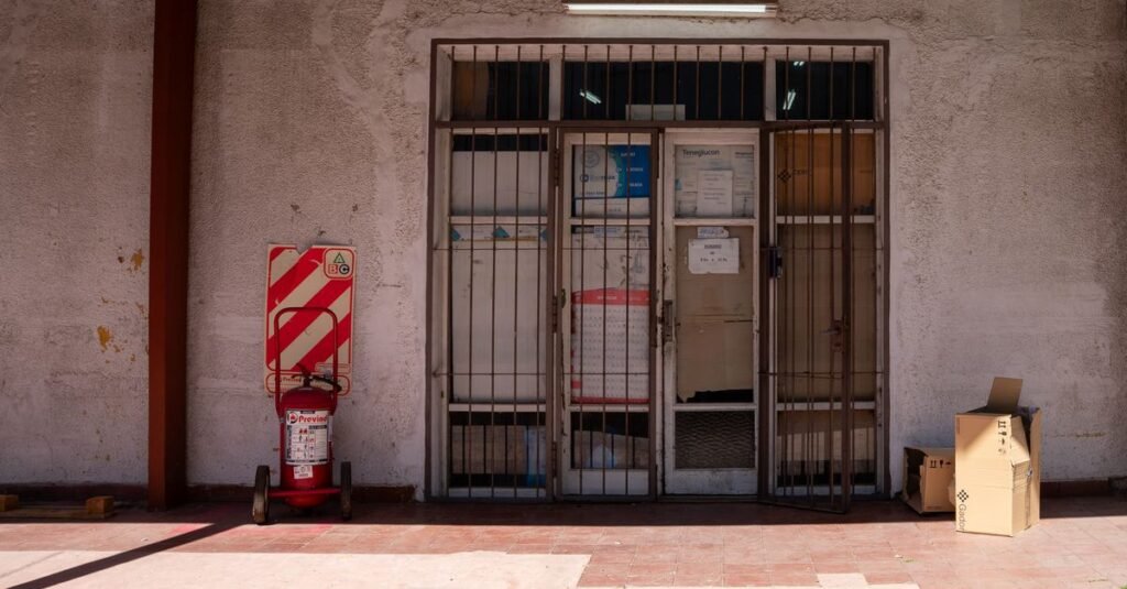 Una verja rústica de hierro en una pared texturizada con un cartel de advertencia, capturada a plena luz del día.