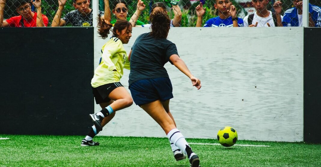 Captura de acción dinámica de mujeres jugando al fútbol en Ciudad de México con espectadores comprometidos.