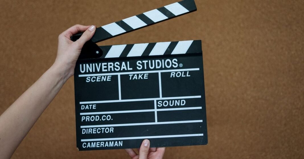 Trump propone un arancel del 100% a las películas hechas fuera de EE.UU. y sacude a Hollywood Primer plano de manos sosteniendo una claqueta de Universal Studios sobre un fondo de corcho, listas para filmar.