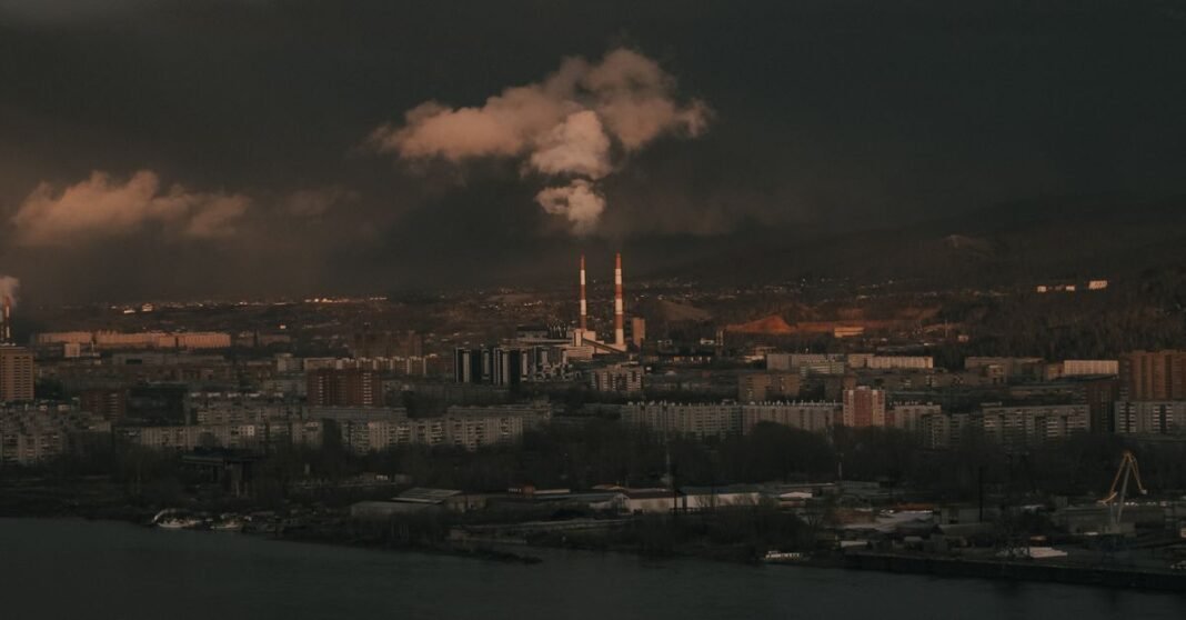 Vista aérea de una zona industrial urbana con chimeneas durante la noche.