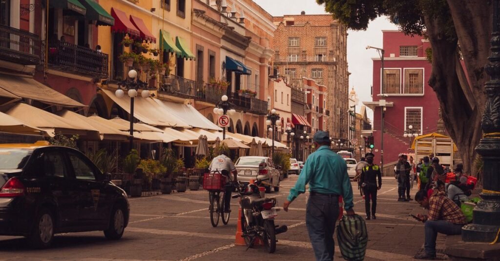 Calle concurrida en la Ciudad de México con ciclistas, peatones y tráfico bajo cielos despejados.