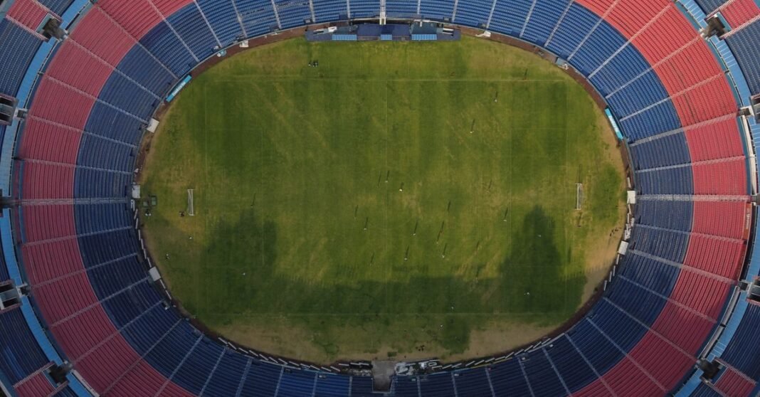 Clara Brugada anuncia operativo de seguridad para la reinauguración del Estadio Ciudad de México y el partido México-Portugal Toma de drone que captura un estadio y el paisaje urbano en Ciudad de México, mostrando edificios y la vida de la ciudad.