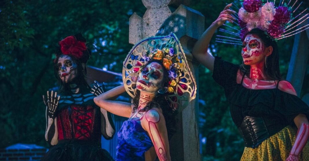 Vibrante celebración del Día de los Muertos con mujeres en atuendos tradicionales de Catrina por la noche.