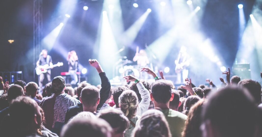 Imagen ilustrativa: Radiohead anuncia 21 conciertos en Australia y Japón para 2027 Escena de concierto enérgica con una audiencia vibrante y banda actuando bajo luces brillantes.