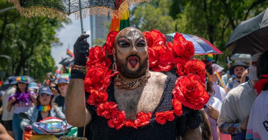 Colorido desfile del orgullo con una artista drag con maquillaje y disfraz atrevidos bajo un cielo soleado.