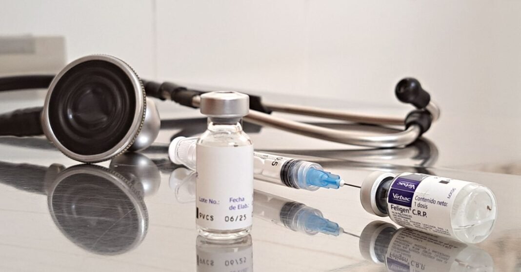 Primer plano de un trabajador de la salud llenando una jeringa desde un vial, demostrando vacunación o procedimiento médico.