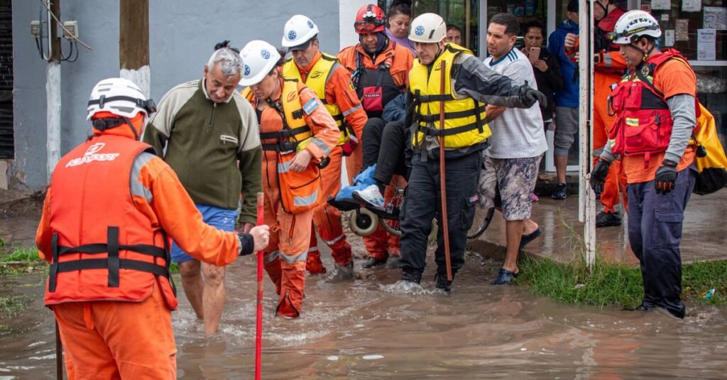 Los servicios de emergencia ayudan a las personas durante una operación de rescate por inundación en la calle.