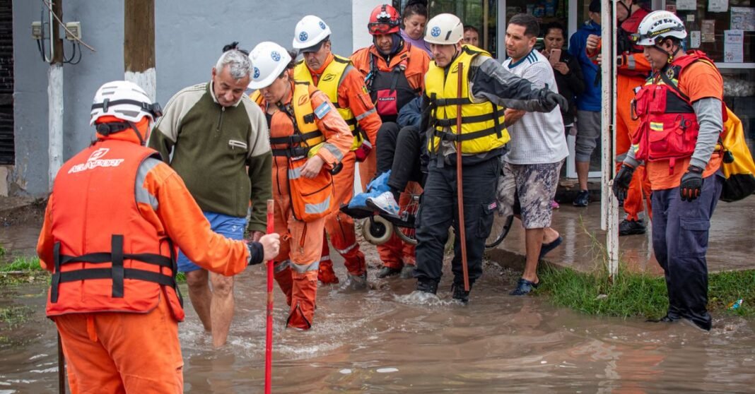 Los servicios de emergencia ayudan a las personas durante una operación de rescate por inundación en la calle.