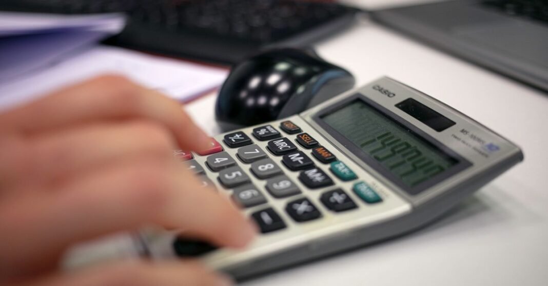 Paquete Económico 2027 será entregado en San Lázaro con foco en evasión fiscal y factureras Primer plano de una mano usando una calculadora en un escritorio para cálculos precisos.