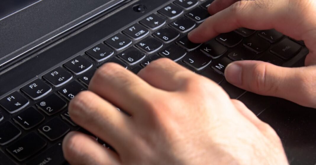 La mitad de los internautas en México ya usa herramientas de inteligencia artificial, según la AIMX Vista detallada de manos escribiendo en un teclado de laptop, ilustrando tecnología y trabajo.