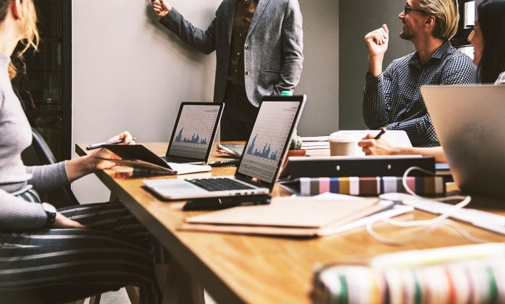 Sala de reuniones de negocios con documentos y personas conversando, usada como imagen ilustrativa.